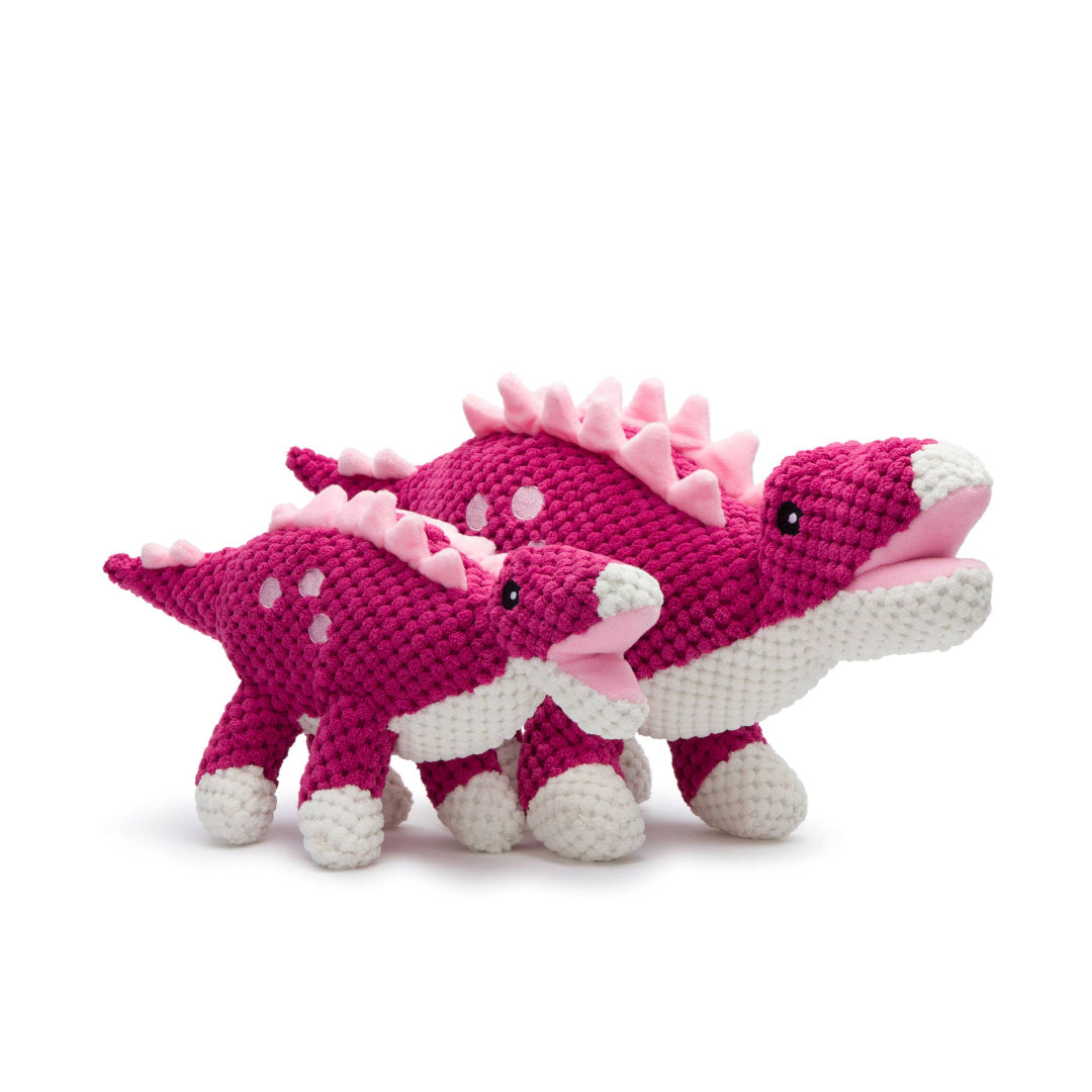 Floppy stegosaurus dog toy with bright pink plush fabric, designed for squeaky fun and cozy snuggles.